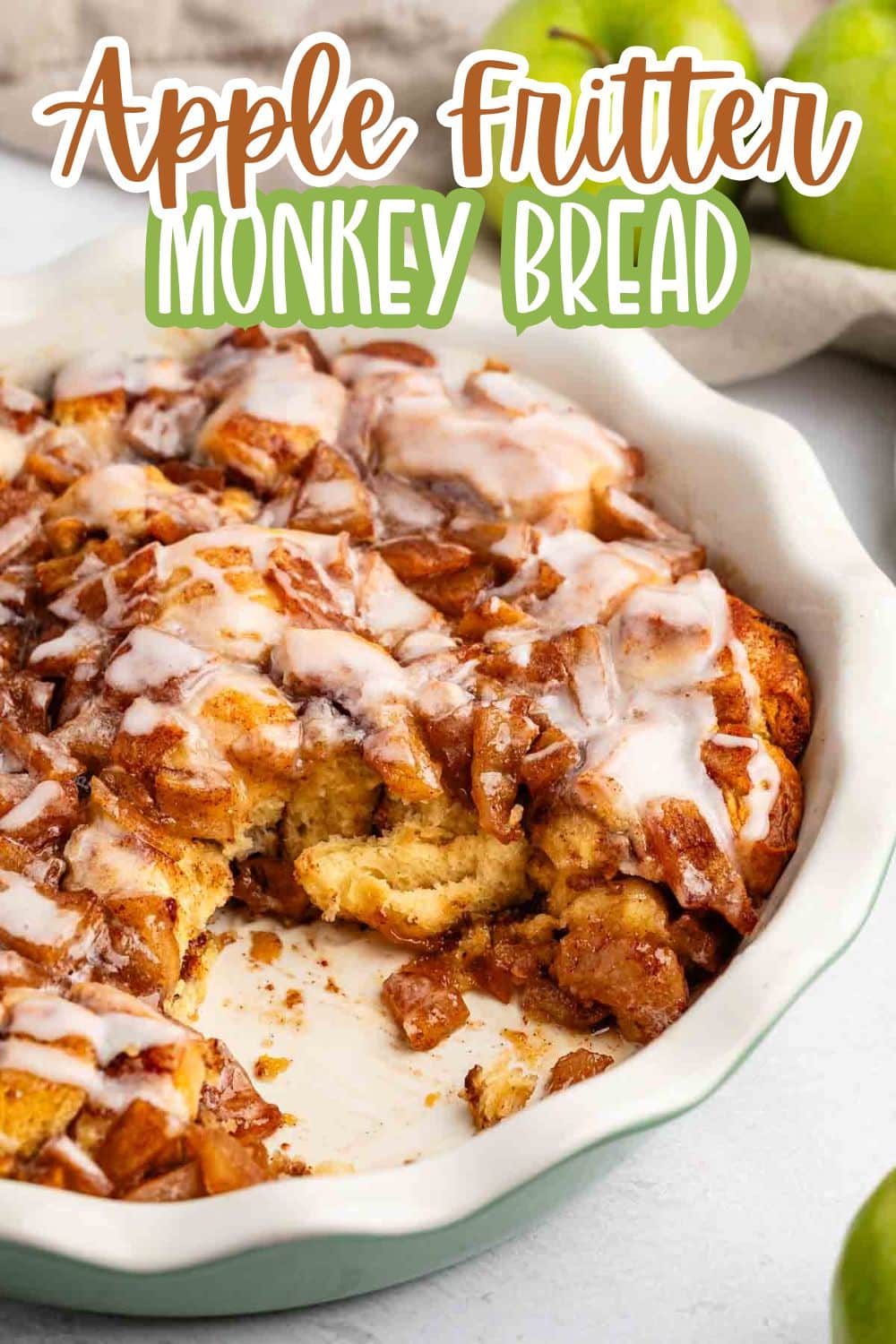 A dish of apple fritter monkey bread is shown with a section removed, revealing soft, doughy bread pieces coated in cinnamon, apples, and icing drizzle. The text “Apple Fritter Monkey Bread” appears at the top.
