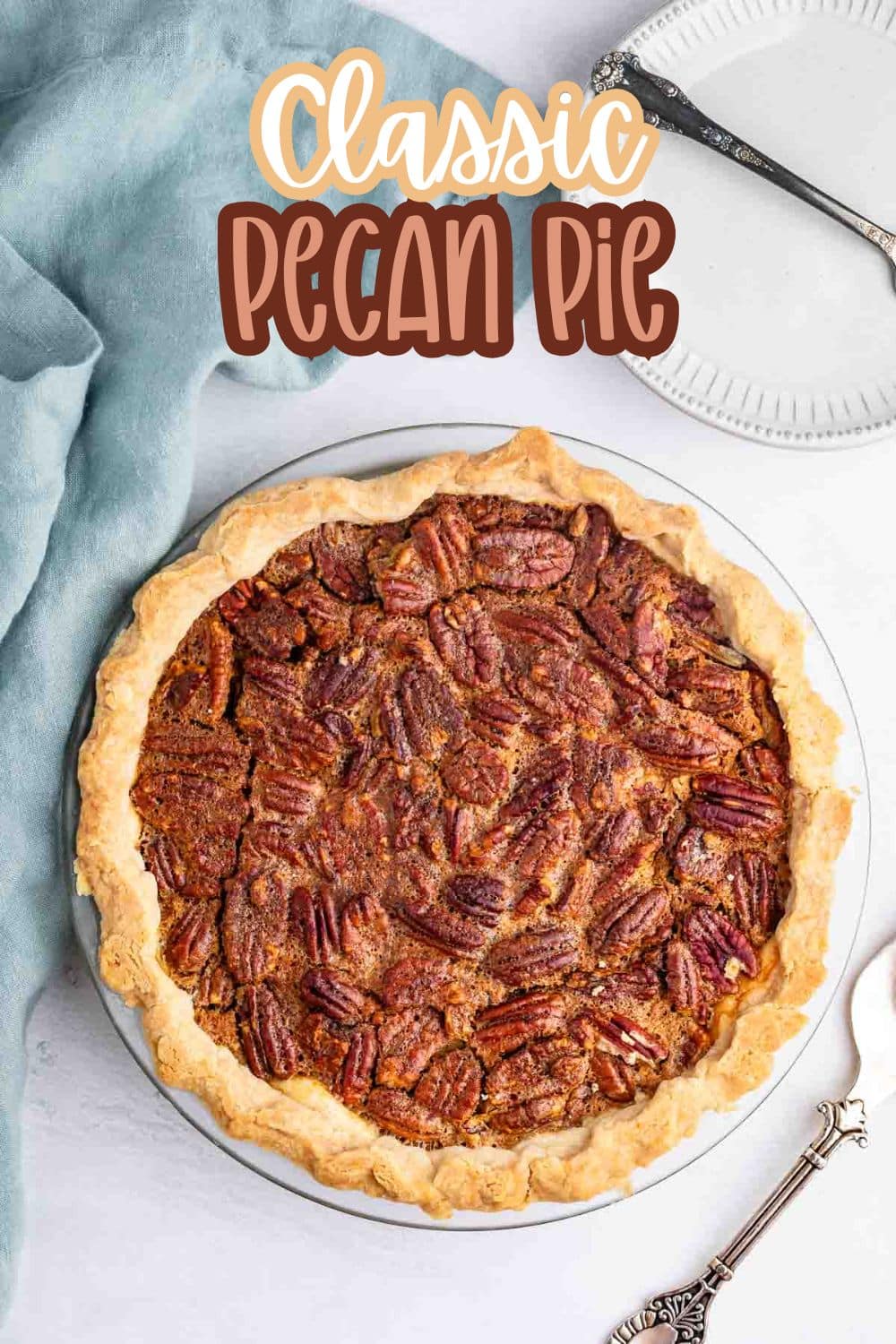 A whole pecan pie with a golden, flaky crust sits on a white surface next to a blue cloth, a decorative pie server, and a white plate. Text on the image reads, Classic Pecan Pie.