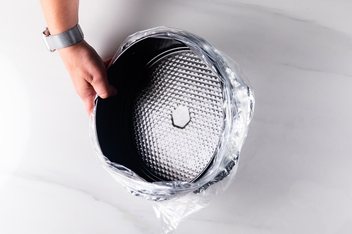 hand holding pan wrapped with foil and place in a bag.