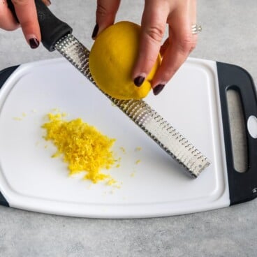Overhead shot of lemon being zested over a cutting board